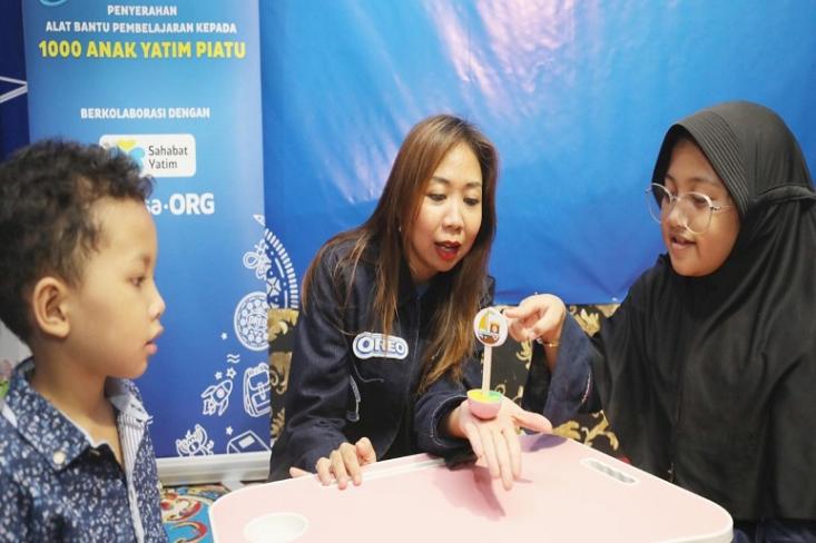 Anggya Kumala bermain bersama anak-anak Sahabat Yatim, mencoba playful learning tools dari kolaborasi OREO dan Surya Institute, anak-anak mendapat bantuan laptop, tas, dan alat tulis juga (Foto: Ist) 