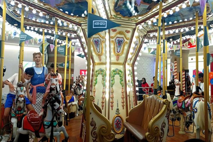 Mikaila Patritz bersama anak-anaknya sedang menaiki komidi putar Kenzo Carousel dalam Kawaii Carnival, sebagai bagian dari peluncuran koleksi KENZO Kids Spring-Summer 2026 bertema Happy Sweet di Plaza Indonesia (Foto: Efa)