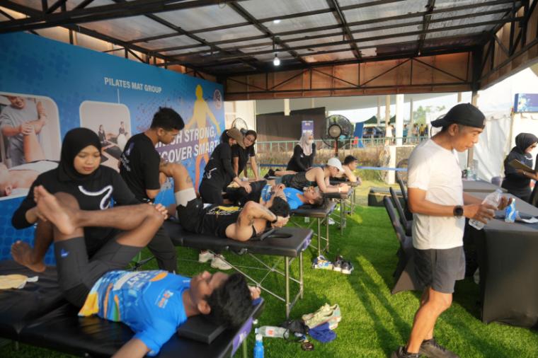 Para peserta mendapatkan layanan pemulihan tubuh melalui sesi stretching dan pijat di booth Recovery